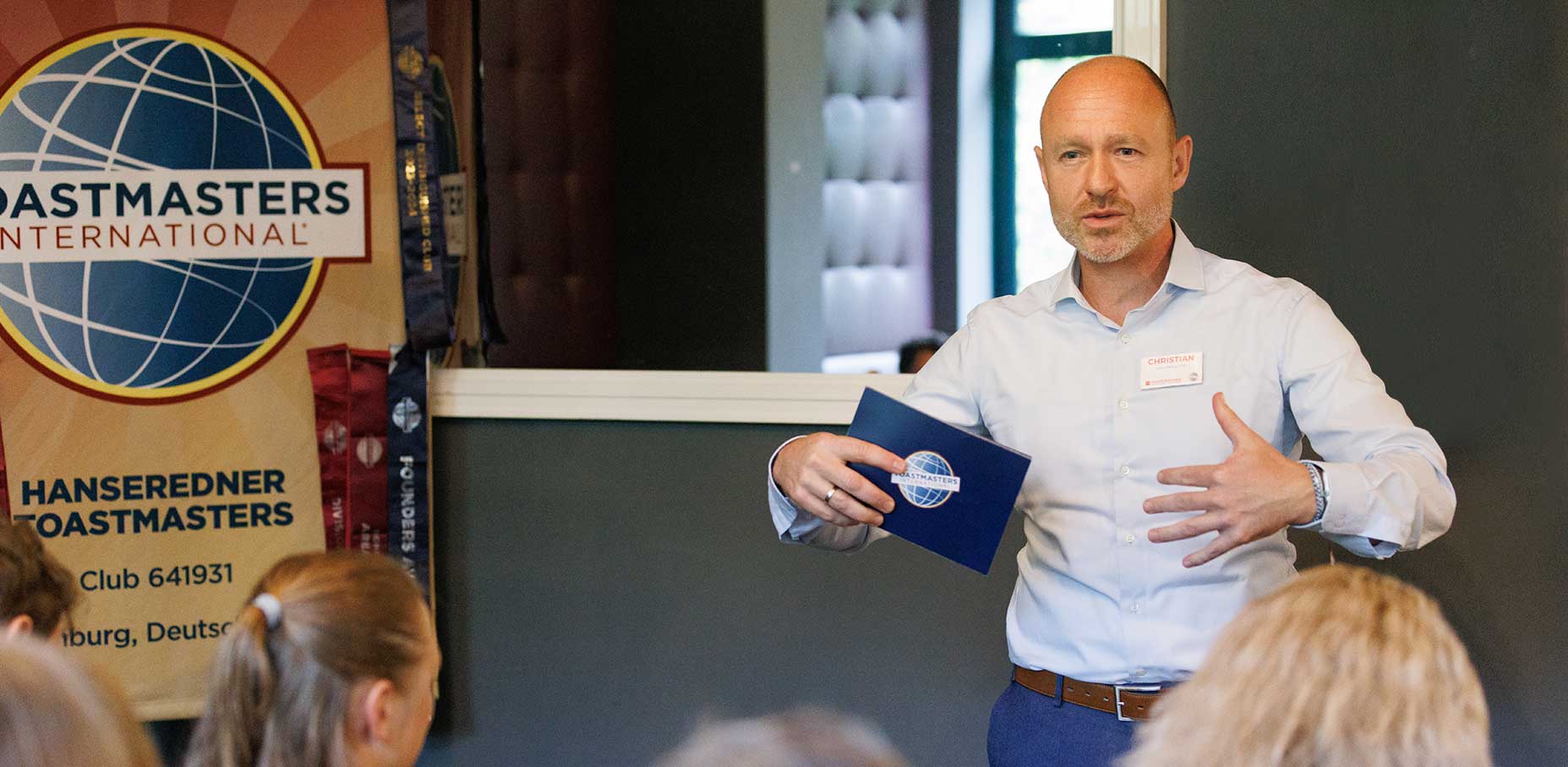 hanseredner-toastmasters-hamburg-rede-training Mitglied der Hanseredner Hamburg spricht vor Publikum beim Toastmasters-Treffen.